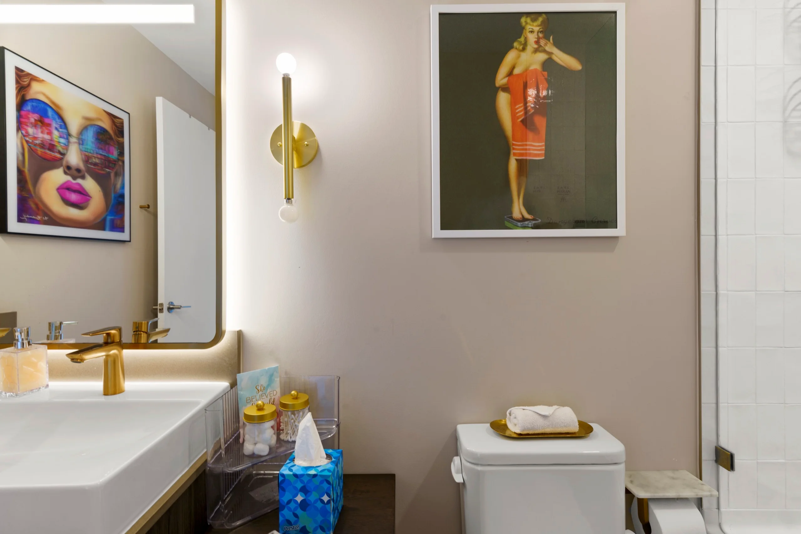 Powder room with brass sconces, vessel basin and a framed portrait print above the vanity