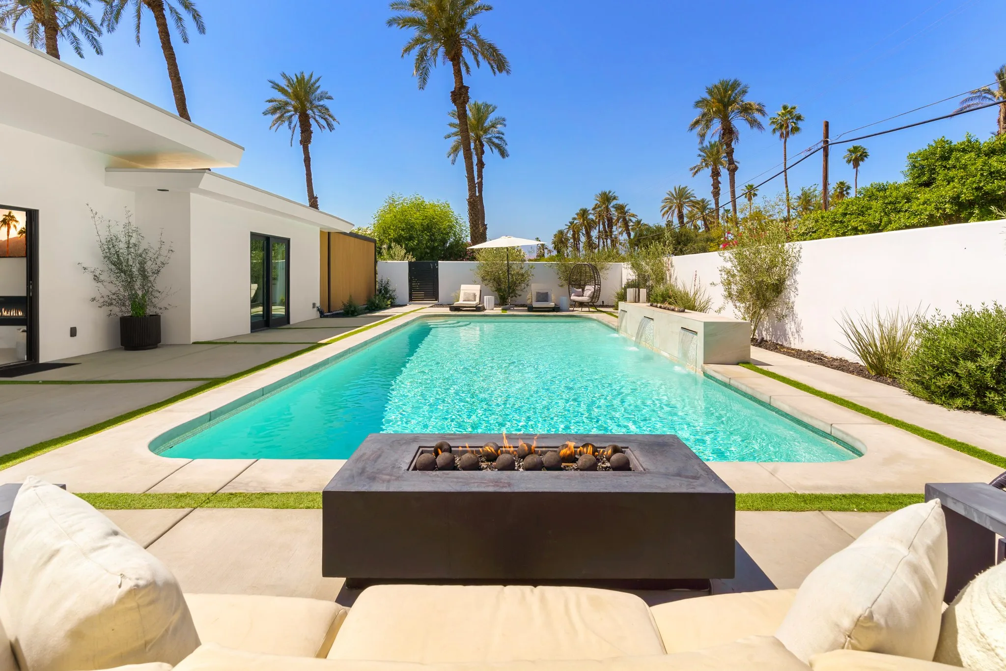 The pool and fire table under palms in the middle of the day, The Villa Palms, Indio, California